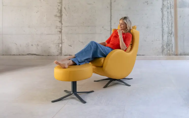 Fotoliu Lenny de la Fama Sofás, în culoare muștar, cu design curbat și taburet, modern și foarte confortabil